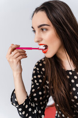 Wall Mural - Pretty girl poses half face with red toothbrush. Healthy teethconcept. White background. Oral care concept.