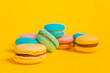 Sweet almond colorful unicorn pink blue yellow green macaron or macaroon dessert cake isolated on trendy yellow modern fashion background. French sweet cookie. Minimal food bakery concept Copy space