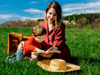 Sticker - mother and son with a book sitting on meadow.