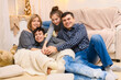 © soleg - portrait of a family sitting on a sofa at home, four people having fun together