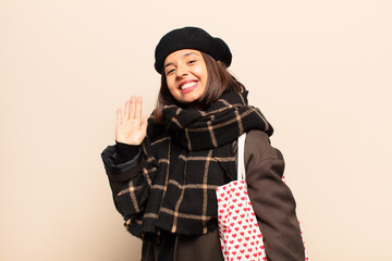 Canvas Print - hispanic woman smiling happily and cheerfully, waving hand, welcoming and greeting you, or saying goodbye