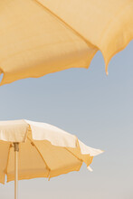 Two Beige Cotton Beach Umbrellas Against A Blue Sky