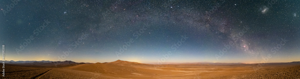 An amazing panoramic view of the Milky Way above Atacama Desert vast sand fields. An awe night sky view with our galaxy arm creating an arch in between the stars. An idyllic and motivational scenery. - obrazy, fototapety, plakaty 