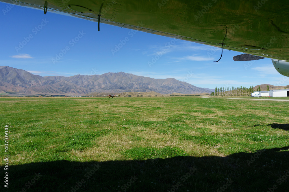 Scenic mountains framed by plane wing and shadow - obrazy, fototapety, plakaty 