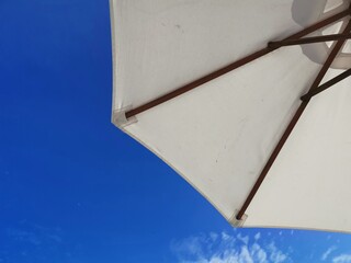 White beach umbrella and blue sky background.