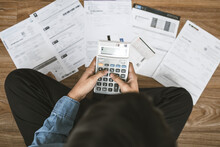 Top View Man Sitting On The Floor Stressed And Confused By Calculate Expense From Invoice Or Bill, Have No Money To Pay Thinking Of Taking The House To Mortgage Causing Debt, Bankruptcy Concept.