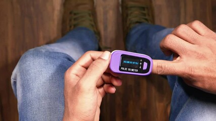 Wall Mural - man sitting on chair using pulse oximeter, top view 