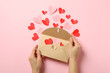 Female hands hold envelope on pink background with decorative hearts