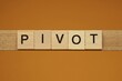 gray word pivot made of wooden square letters on brown background