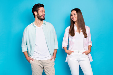 Poster - Photo of shiny sweet young lovers dressed casual shirts looking each other hands arms pockets isolated blue color background