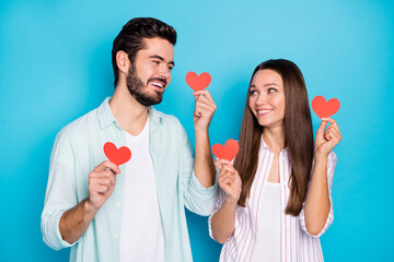 Portrait of handsome guy charming lady look each other hold red paper heart symbols isolated on blue color background