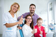 © didesign - Satisfied family with a smiling young female dentist