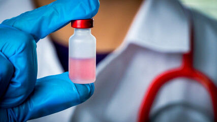 Doctor or scientist carries a vial of liquid vaccine for children and adults to test for COVID-19 vaccine in the lab. Concept COVID-19 vaccine