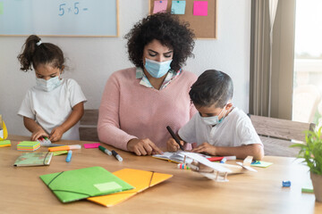 Teacher helping children inside preschool wearing safety masks during coronavirus outbreak - Focus on boy face