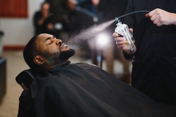 Black man in the barbershop. Cute black man makes a haircut in the African salon. Hair style. Haircut for adults.