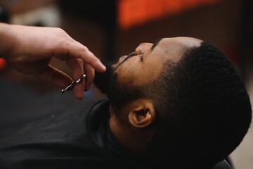 Black man in the barbershop. Cute black man makes a haircut in the African salon. Hair style. Haircut for adults.