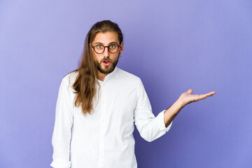 Young man with long hair look impressed holding copy space on palm.