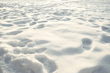 Snow drifts illuminated by the sun, human footprints in the snow. Abstract background. Space for copying.