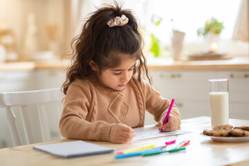 Wall Mural - Indoor Portrait Of Small Adorable Girl Drawing Picture At Table In Kitchen