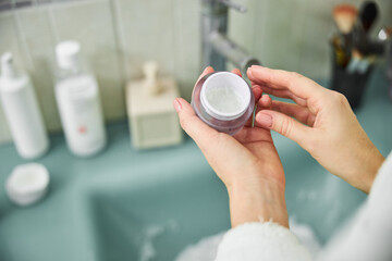 Wall Mural - Woman using cosmetics face cream in bathroom