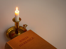 Hebrew Bible In The Light Of A Candle On A Brass Stick