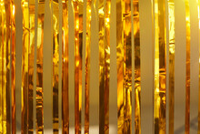 Fun Party Decor Concept. Festive Background Of Shiny Metallic Tinsel Strands. Closeup Of Gold Foil Fringe Curtains At A Photo Booth. Close-up Of Bright Golden Mylar Holiday Decoration Hanging Off Door
