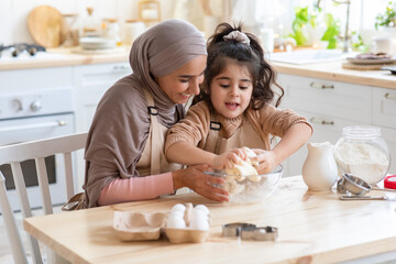 Wall Mural - Adorable Little Girl And Her Muslim Mom Cooking In Kitchen, Kneading Dough