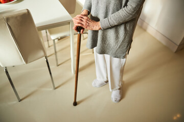 Woman in pants and a tunic using a cane