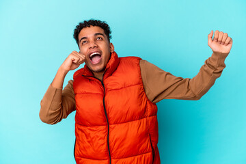 Young african american curly man isolated on blue dancing and having fun.