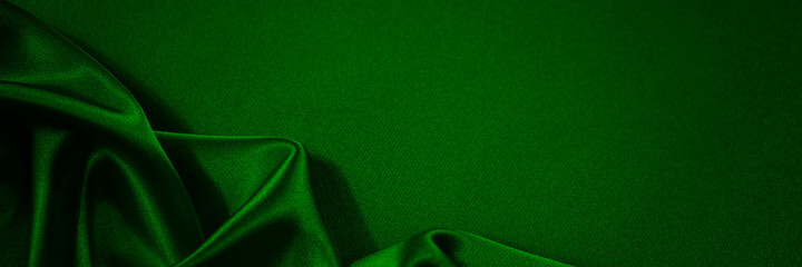 Wall Mural - Black green silk satin background. Copy space for text or product. Wavy soft folds on shiny fabric. Luxurious dark green background. Christmas. Anniversary. Black Friday. Web banner.