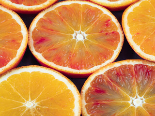 Colorful fruit background top view. slices of red orange are on dark dish . Top view of orange background. Fresh citrus fruit rich of vitamins, juicy fruit, healthy nutrition. Orange color