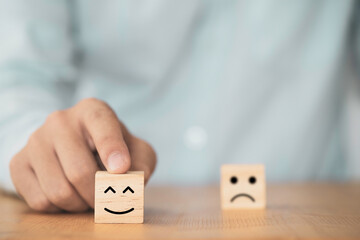 Poster - Businessman use finger to pointing smile face which print screen on wooden cube block , Emotion and mindset concept.