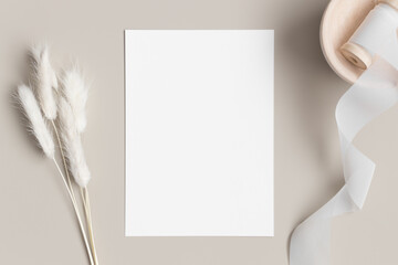 white invitation card mockup with a lagurus on the beige table. 5x7 ratio, similar to a6, a5.