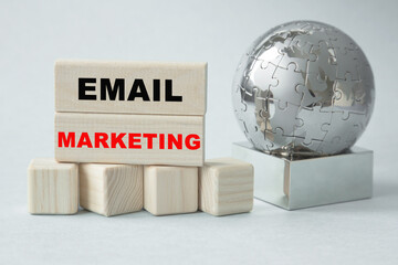 Text EMAIL MARKETING. Globe and wooden cubes on a gray background. The concept of world business, marketing, finance.