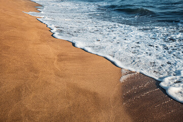 Wall Mural - Foam wave and yellow sand. The concept of a holiday by the sea and surf