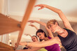 © Vladimir Borovic - Beautiful adult women doing exercises on stretching ballet bar in Pilates class. Group of females doing yoga, pilates and fitness exercise indoors in studio.