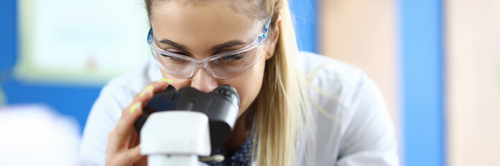 A researcher in a laboratory looks at samples through a microscope. Biologist conducts chemical-technological control