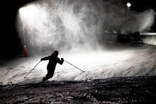 Silhouette Of A Telemark Skiier At Night In A Ski Resort Under A Snow Cannon