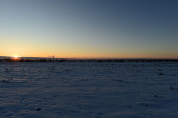 Wall Mural - Sunset in the blue clear frost sky over a snowy field