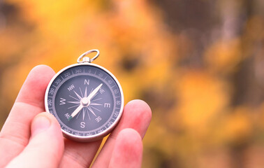 old classic navigation compass in hand on natural background as symbol of tourism with compass, trav
