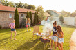 © Impact Photography - Friends grilling meat and playing frisbee at backyard barbecue party