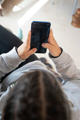 Girl with several braids in her hair using her smartphone while sitting