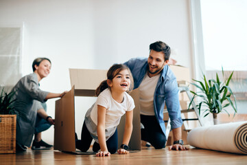 Wall Mural - Playful girl and her parents having fun while moving into a new house.