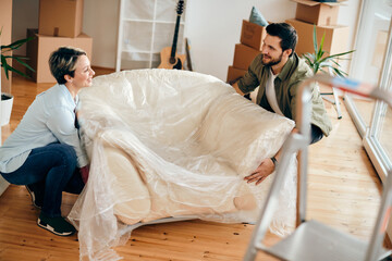 Wall Mural - Happy couple carrying armchair in their new apartment.