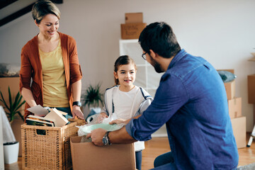 Wall Mural - Happy family communicating while unpacking carboard boxes at their new home.