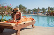 © timonko - Woman in a straw hat relaxing on a daybed near a luxurious summer pool hotel Egypt, concept time to travel