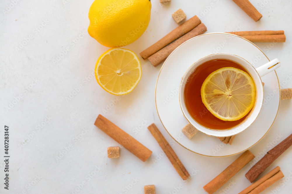 Tasty tea with cinnamon and lemon in cup on light background