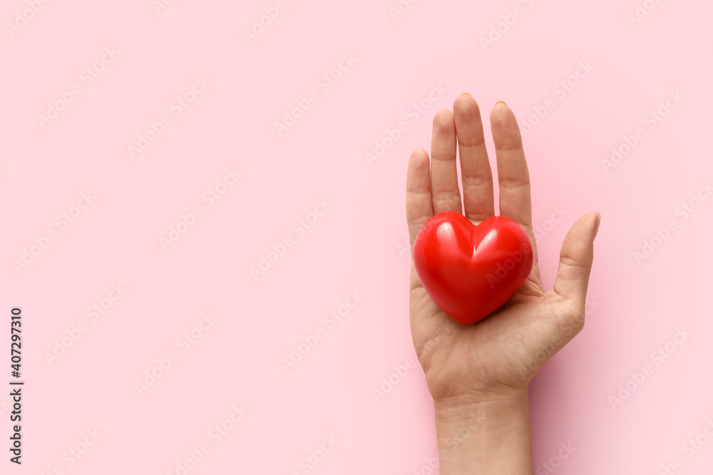 Hand with red heart on color background