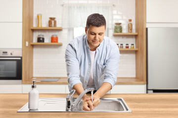 Wall Mural - Man washing hands in a kitchen sink