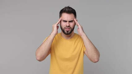 Poster - Sick ill bearded young man 20s years old in yellow casual t-shirt isolated on grey background studio. People lifestyle concept. Put hands on head rub temples having headache migraine feel bad seedy